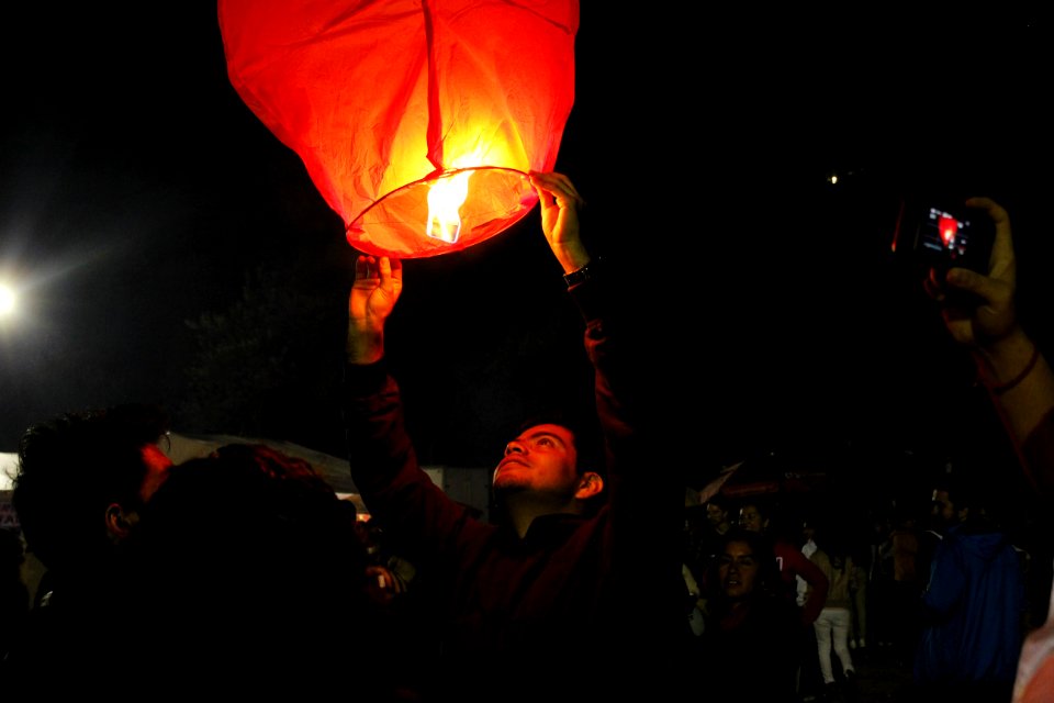 man holding lighted sky lantern
