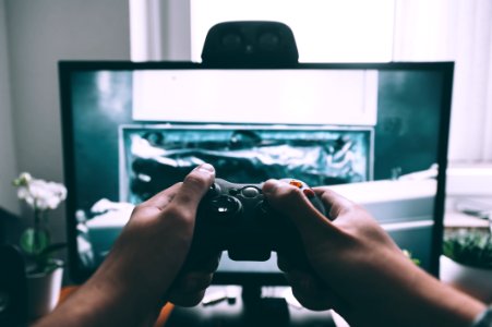person holding game controller in-front of television photo