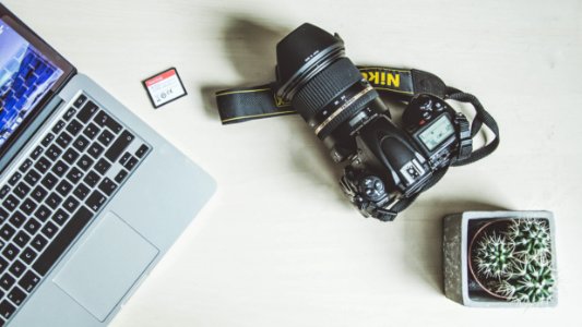 black nikon dslr camera beside silver macbook photo