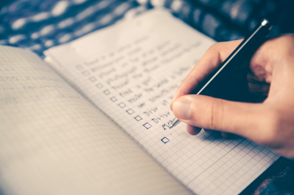 person writing bucket list on book photo