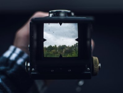 black camera taking photo of green trees during daytime photo