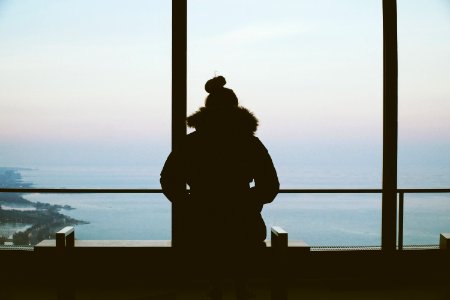 silhouette of woman standing overlooking body of water photo