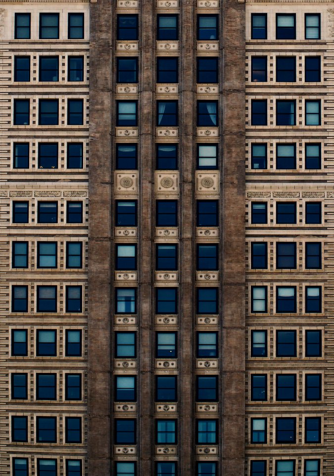 brown concrete building with blue glass windows during daytime photo