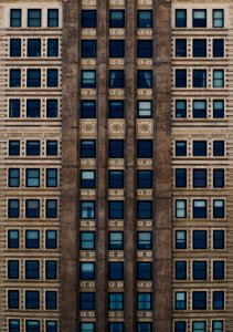 brown concrete building with blue glass windows during daytime