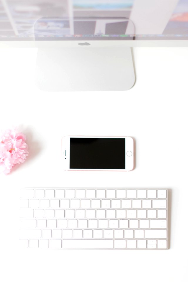 A flatlay image of a smartphone next to a Mac monitor and keyboard.