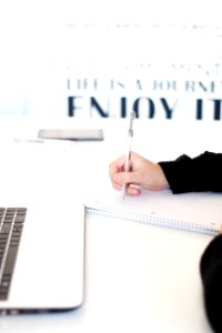 A person writing on a piece of paper, with a motivational quote in the background. photo