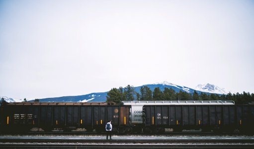 man standing on railroad near train photo