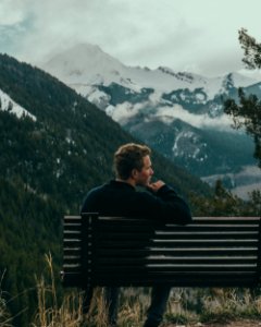 man sitting on bench on top of the mountain photo