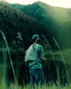 person fishing on body of water near mountain during daytime photo