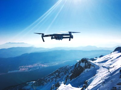 white quadcopter drone flying near snow mountain during daytime photo