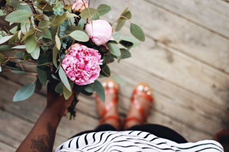 person holding pink flowers standing on brown wooden flooring photo