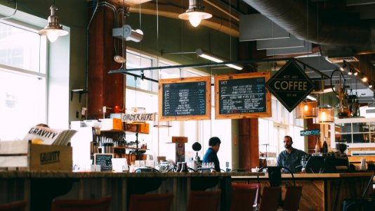 man sitting on bar chair in front man at cafe