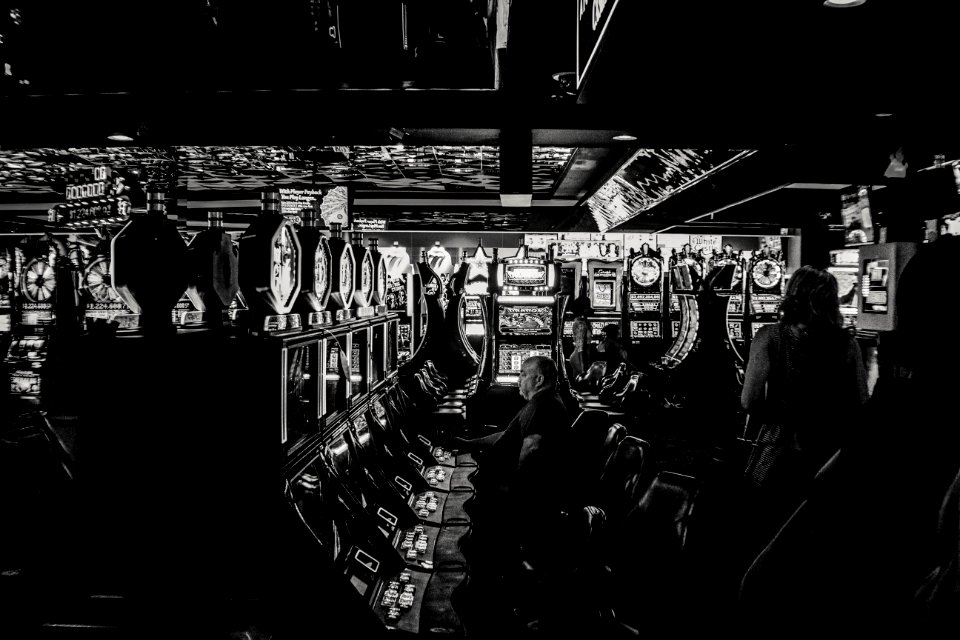 grayscale photo of man playing slot machine