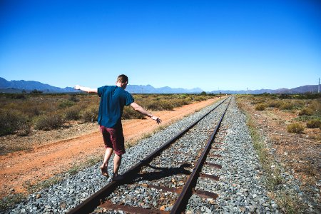 person walking on brown steel train rail outdoor during daytime photo