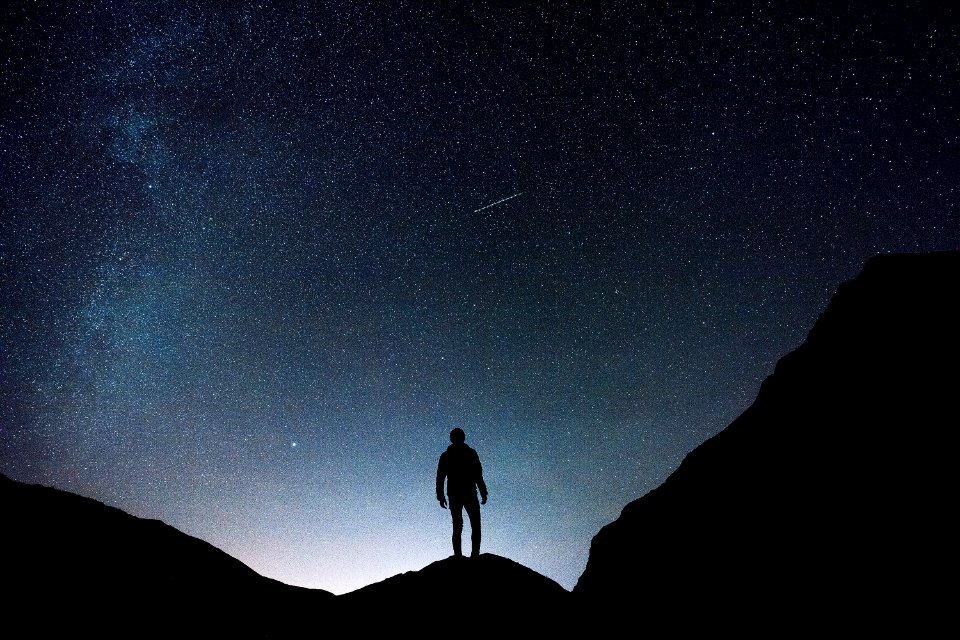 silhouette of man standing on hill during starry night