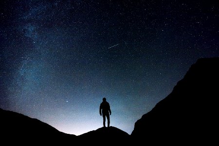 silhouette of man standing on hill during starry night photo