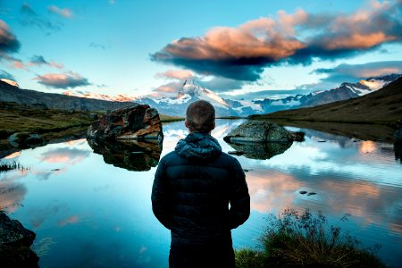 man standing in front view of lake surrounded with mountains photo