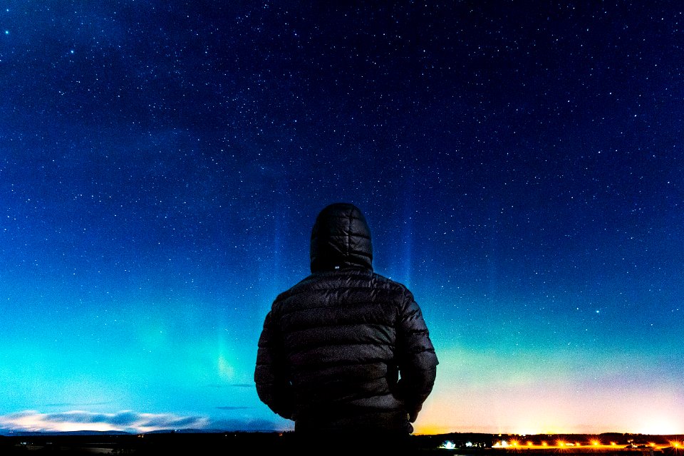 man in black bubble hoodie looking at the stars photo