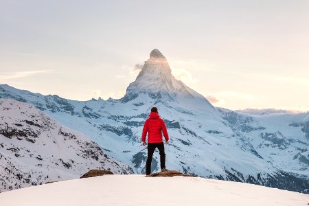 person in red hoodie standing on snowy mountain during daytime photo