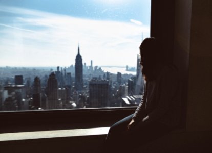 woman sitting on window edge looking at Empire State tower photo