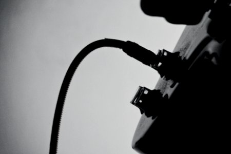 A black-and-white shot of a wire plugged in into a guitar