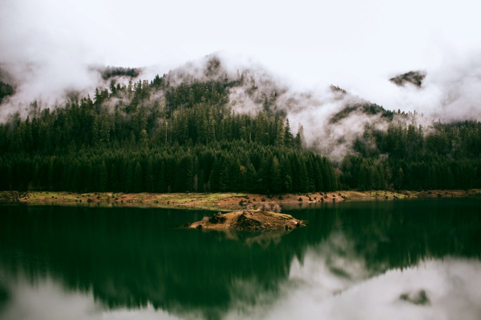 smoke covered mountain near body of water