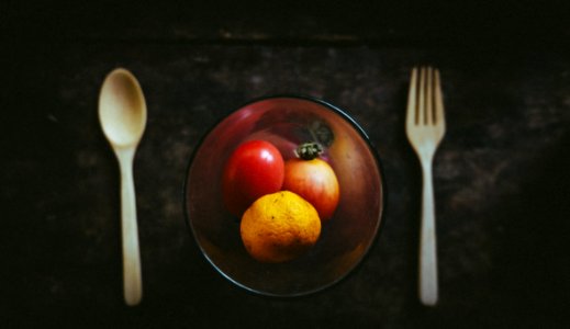 amber glass bowl with fruits besides white spoon and fork photo