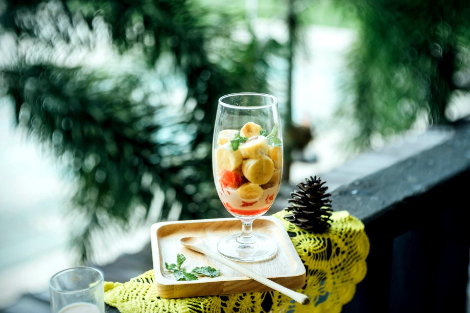 clear footed glass filled with fruits on brown wooden tray photo