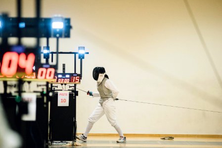 fencer standing near white painted wall photo