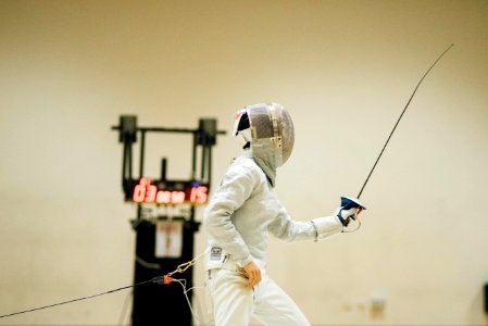 man wearing white coveralls holding fencing sword photo