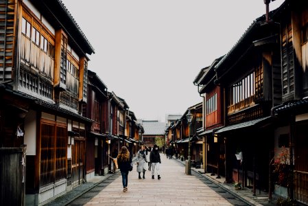 people walking on the street between brown wooden buildings during daytime photo