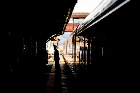 man standing near train in subway during daytime photo
