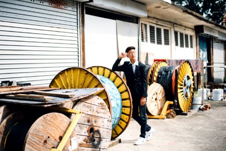 man standing beside spool of cable