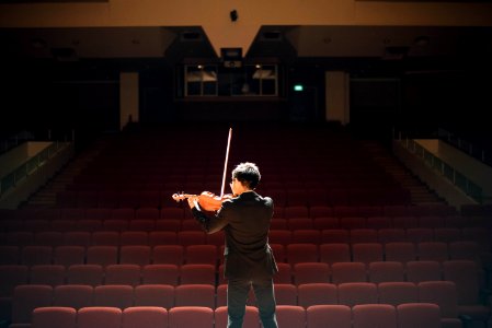 man standing in front of stage playing violin photo