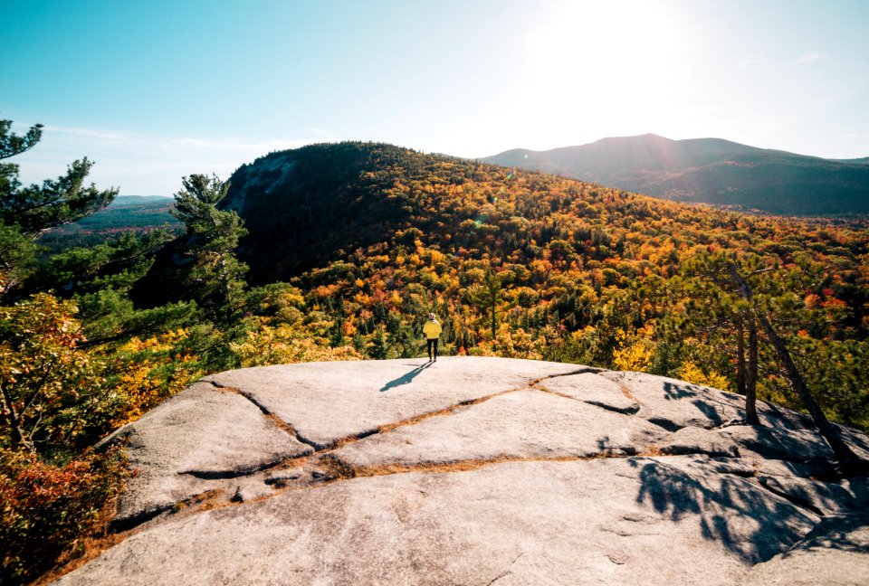 person standing on rock cliff under clear blue skies at daytime