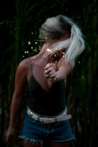 selective focus photo of woman holding sparkler while looking away photo