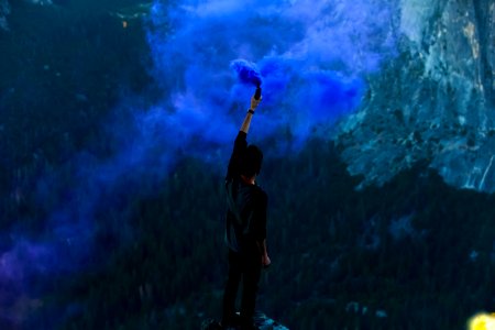 man holding blue powder while raising hand