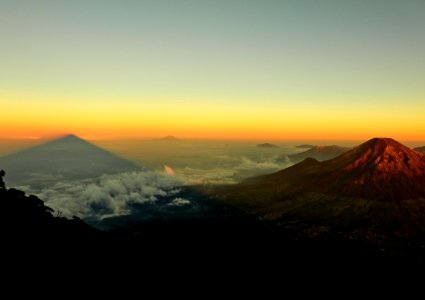 aerial photo of mountain near land covered by white clouds at golden hour