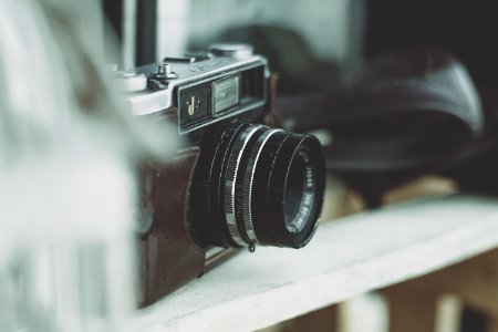 selective focus photography of camera on wooden rack photo