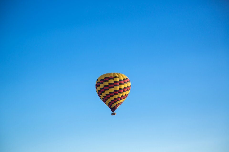 yellow and pink hot air balloon floating under blue sky during daytime