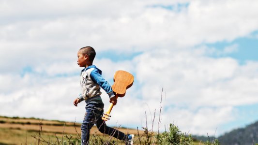 boy running while holding ukelele photo