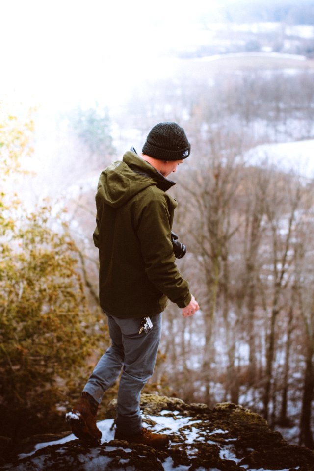 man standing on gray rock formation photo