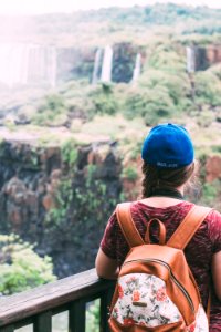 woman in brown leather backpack looking at green trees during daytime photo