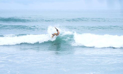 man riding a surfboard facing the waves on the ocean photo
