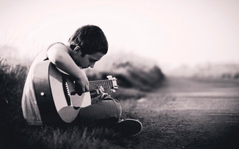 grayscaled photo of boy playing guitar photo