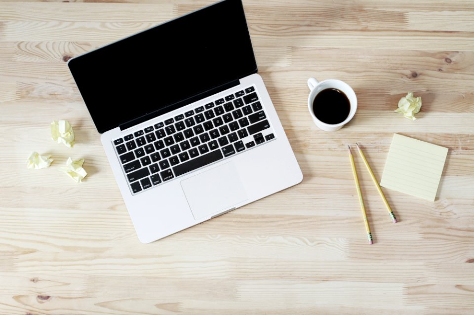 turned off MacBook Pro beside white ceramic mug filled with coffee photo