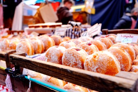 selective focus photography of doughnuts display on brown wooden trays near person wearing black hoodie photo