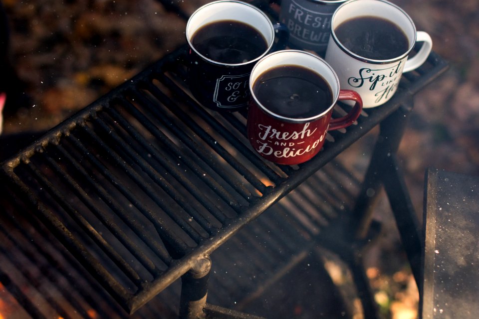four assorted-color ceramic mugs on black grill frame