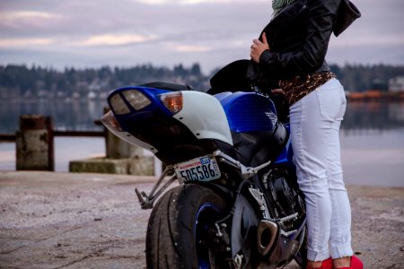 woman standing in front of blue motorcycle