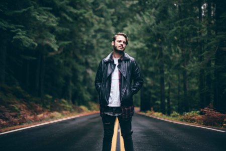 man wearing black zip-up jacket standing in middle of road photo